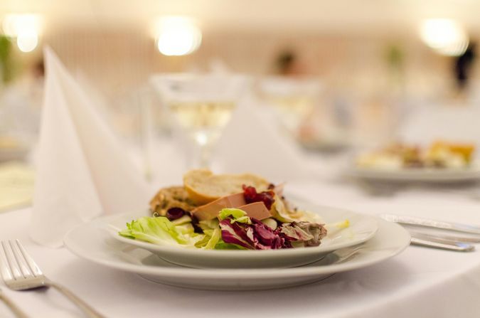 Plate of gourmet salad with bread on a elegantly set restaurant table, perfect for upscale dining experiences.