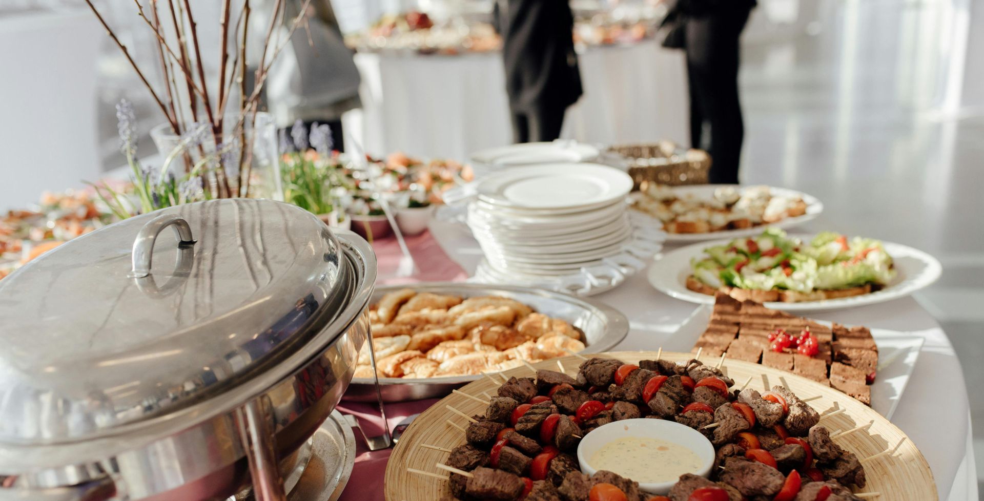 Elegant buffet featuring skewered meats, fresh salads, and assorted desserts at a festive event.