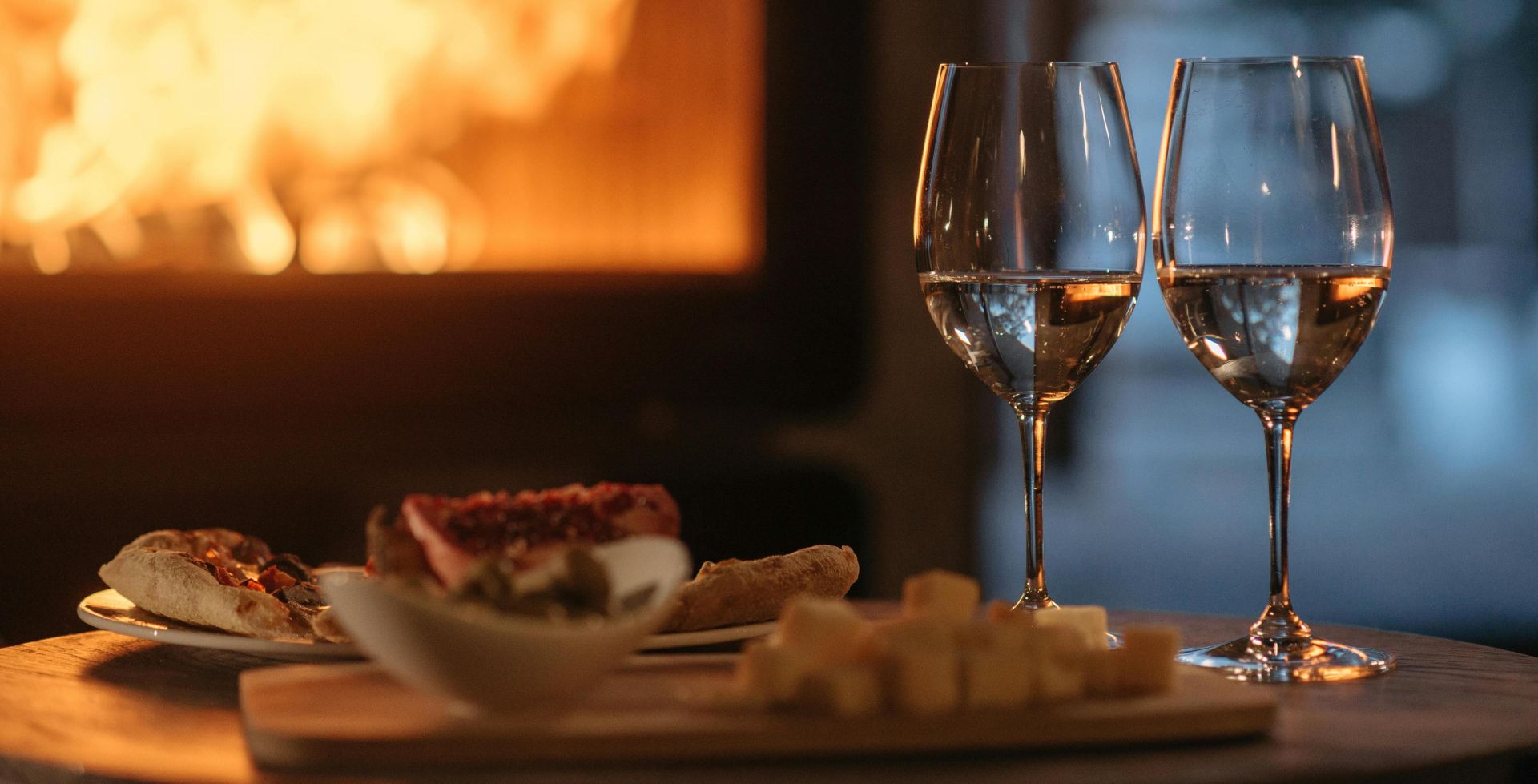 Intimate dining by the fireplace with wine and appetizers, perfect for a cozy winter evening.