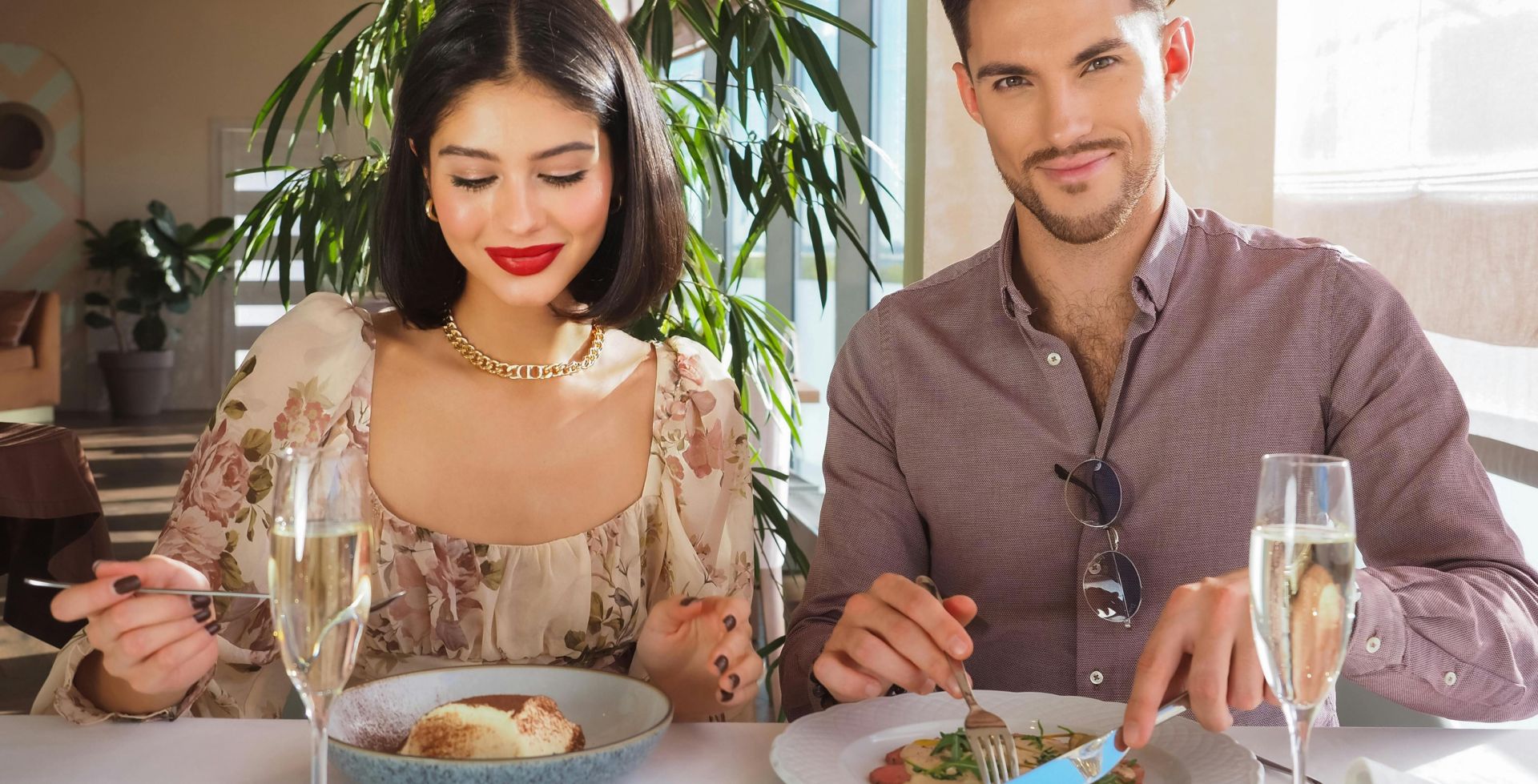Stylish couple enjoying a gourmet meal with champagne at a sophisticated restaurant setting.