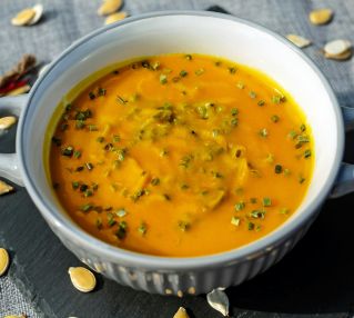 Warm and creamy pumpkin soup garnished with fresh herbs, perfect for a cozy meal.