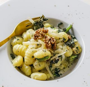 Elegant plate of gnocchi pasta topped with kale and walnuts, perfect for a gourmet meal.